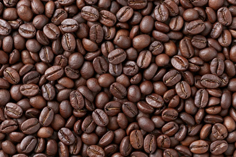 Roasted coffee beans densely spread across a flat surface