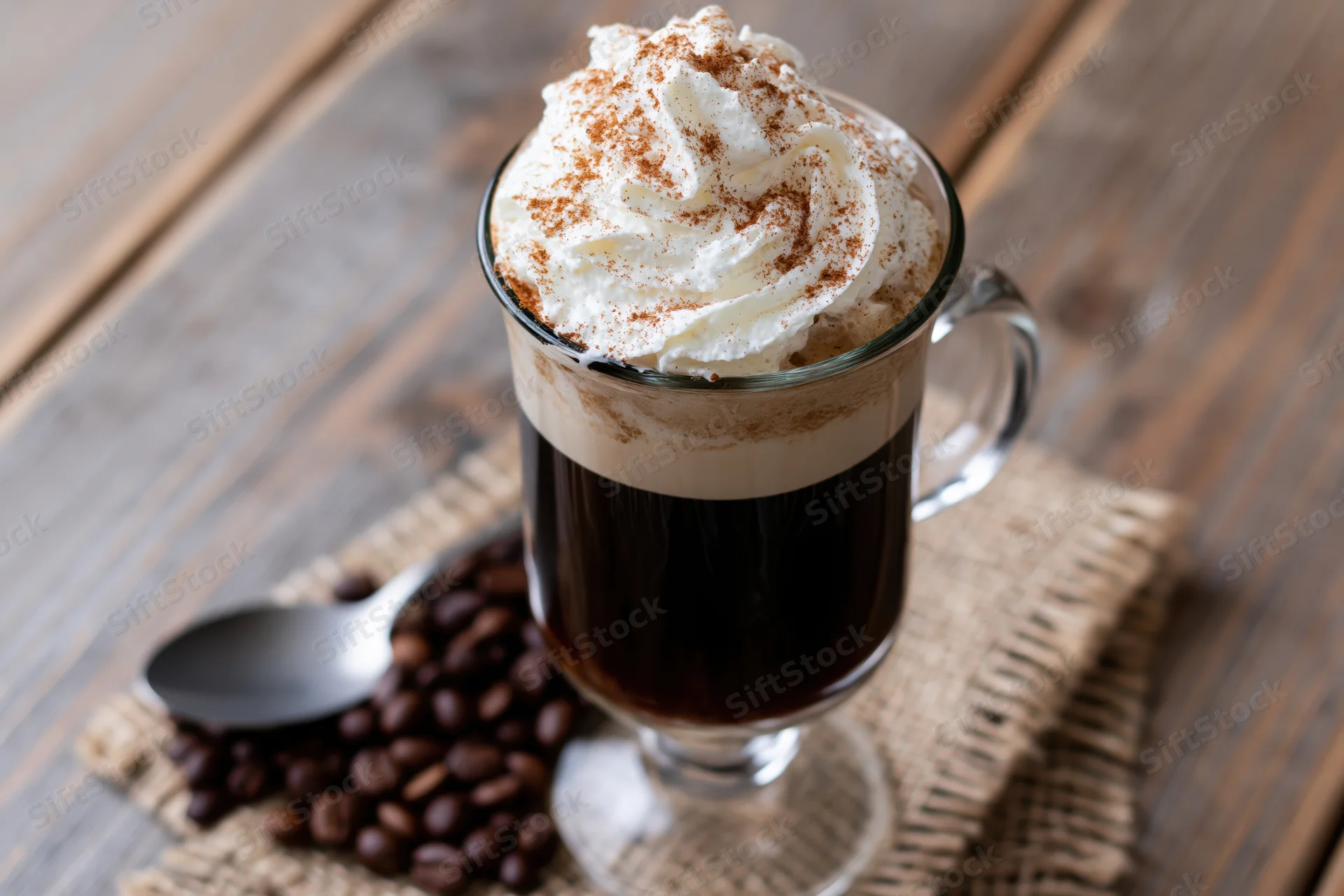 Irish coffee in a tall glass mug with whipped cream and cinnamon on a wooden table