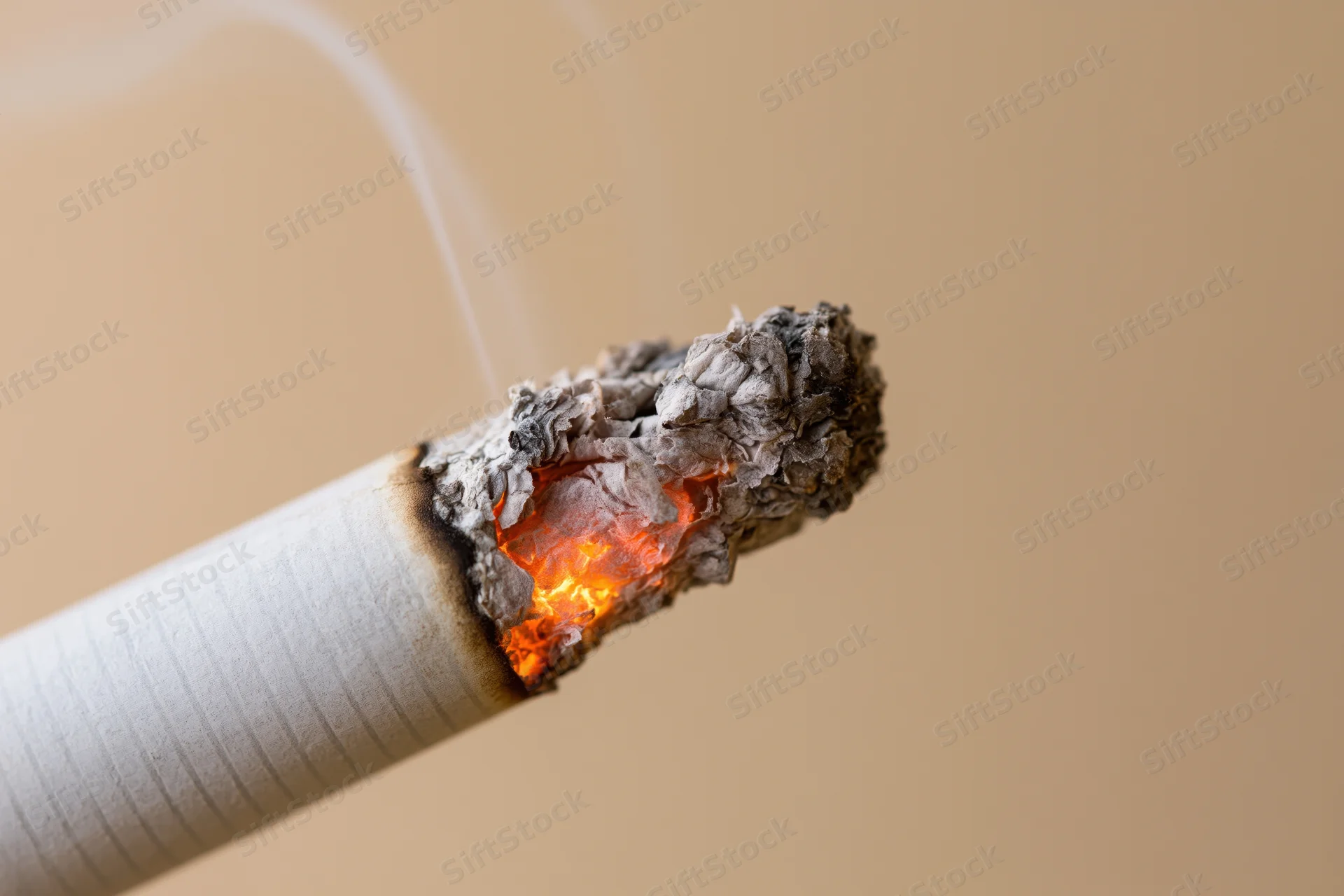 Lit cigarette tip glowing with orange ember and rising smoke in closeup