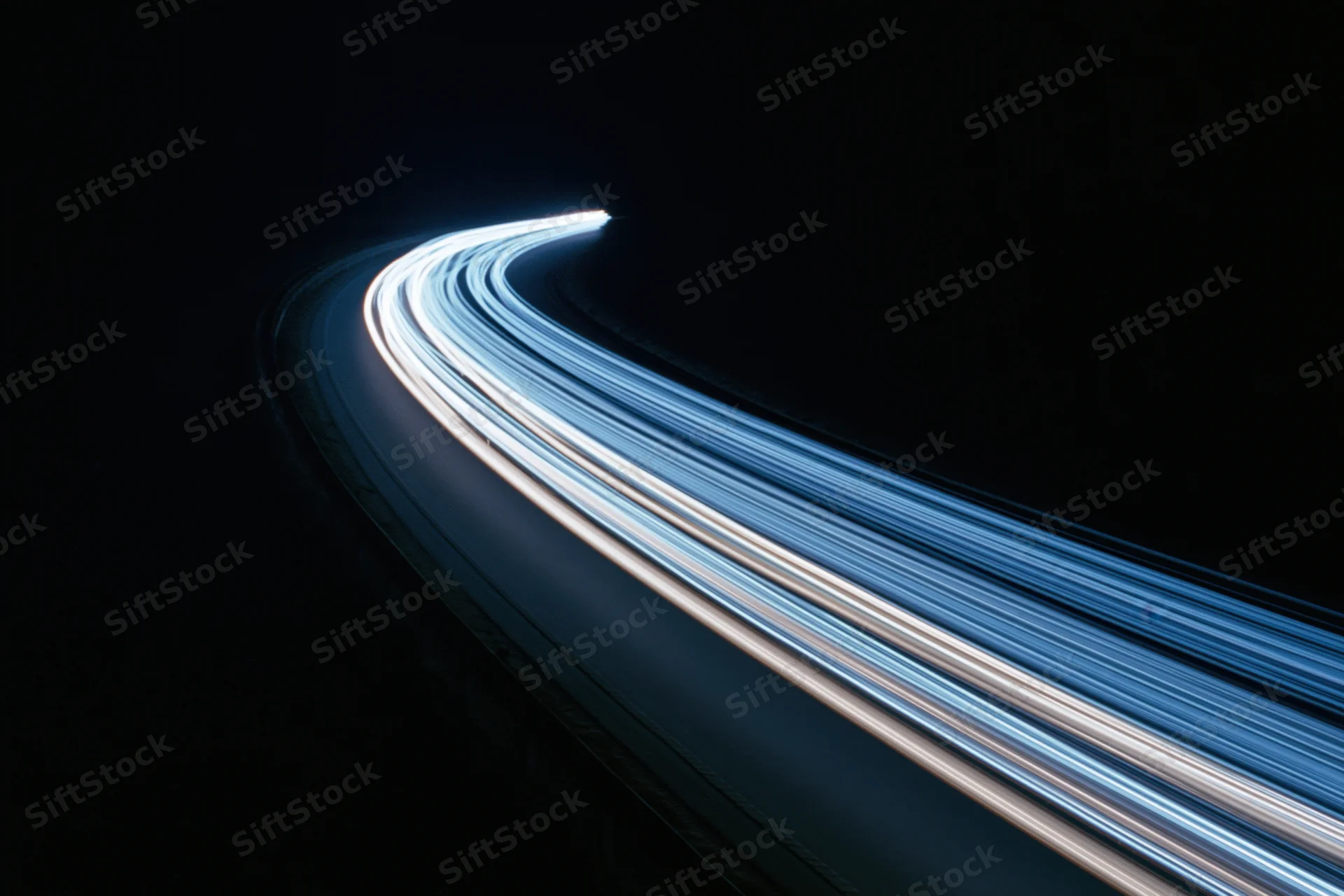 Curved highway at night with light trails from moving vehicles