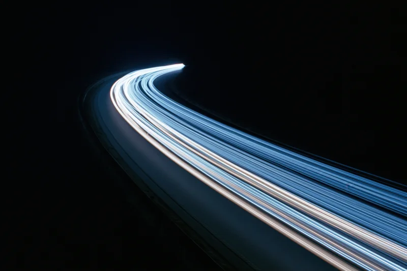 Curved highway at night with light trails from moving vehicles