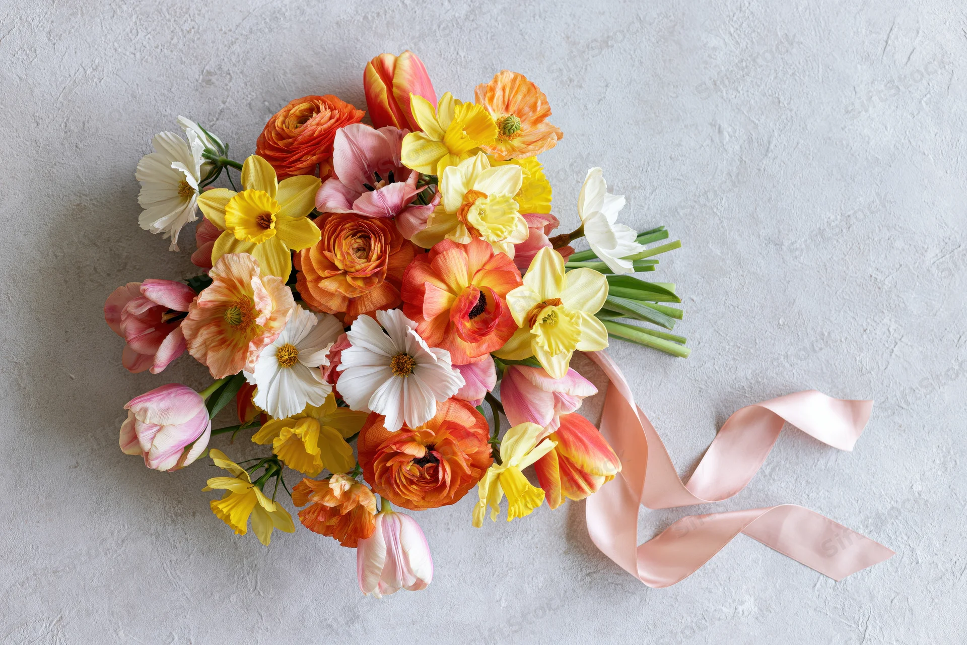 Heart-shaped bouquet of spring flowers with pink ribbon on light textured surface