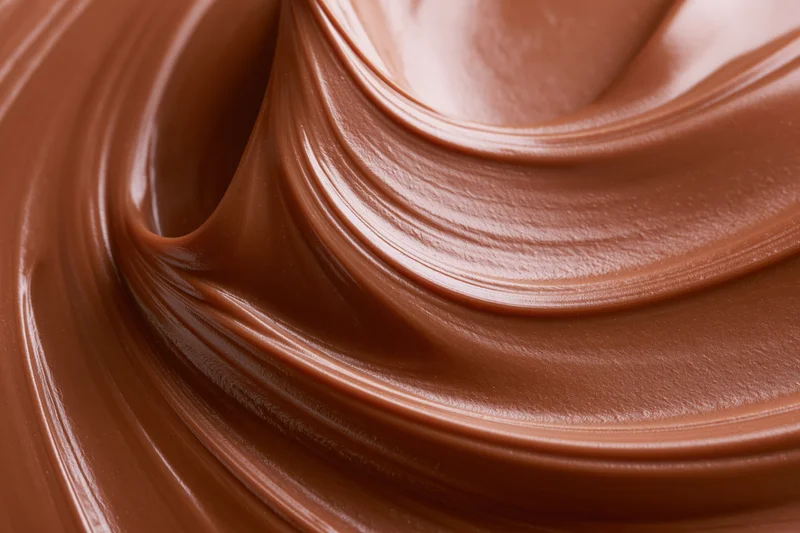 Melted milk chocolate spread in smooth swirls across a flat surface