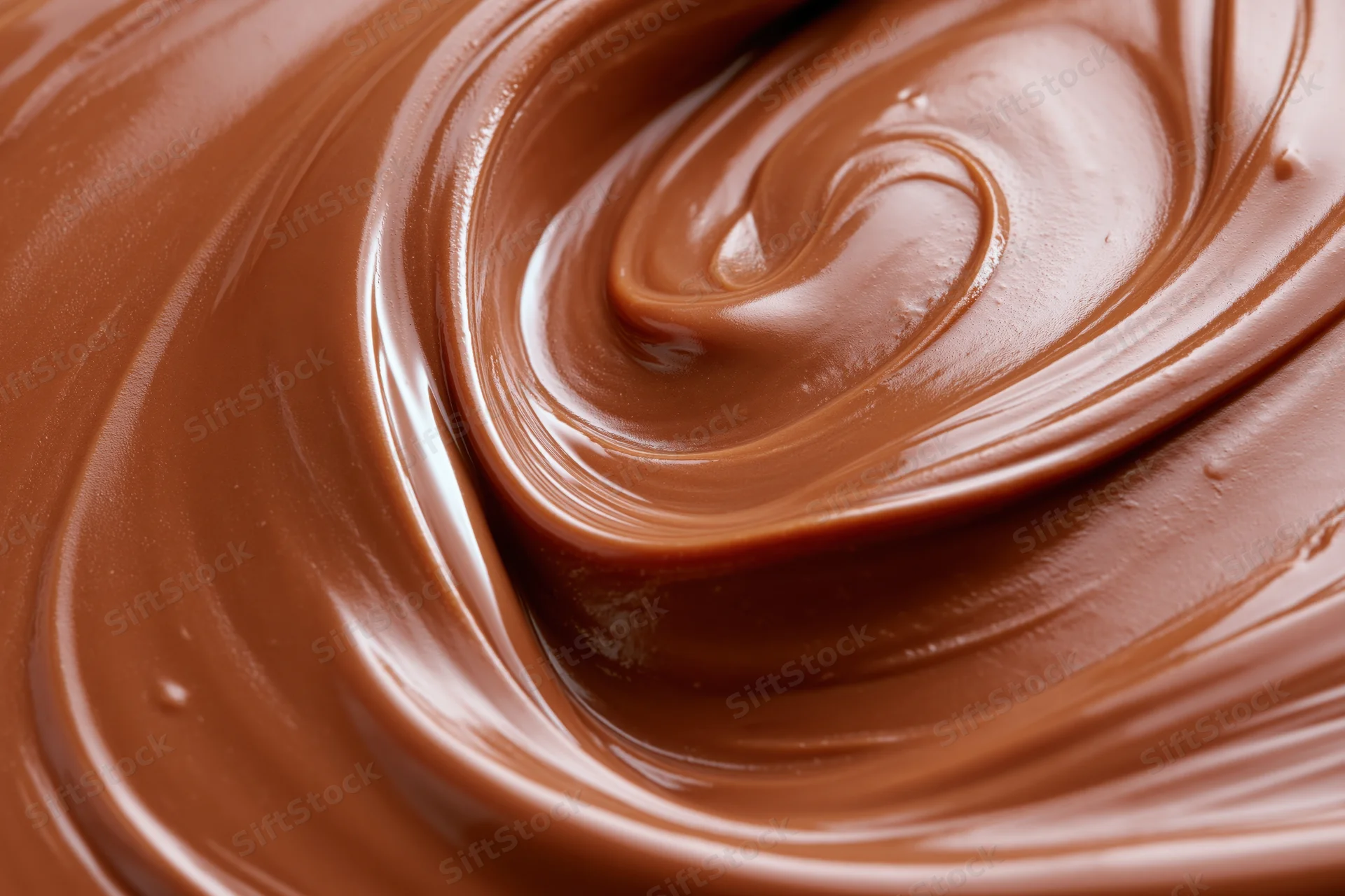 Melted milk chocolate spread in smooth swirls across a flat surface