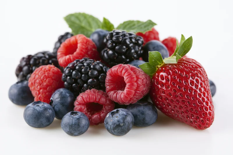 Mixed fresh berries arranged in a loose pile on white background