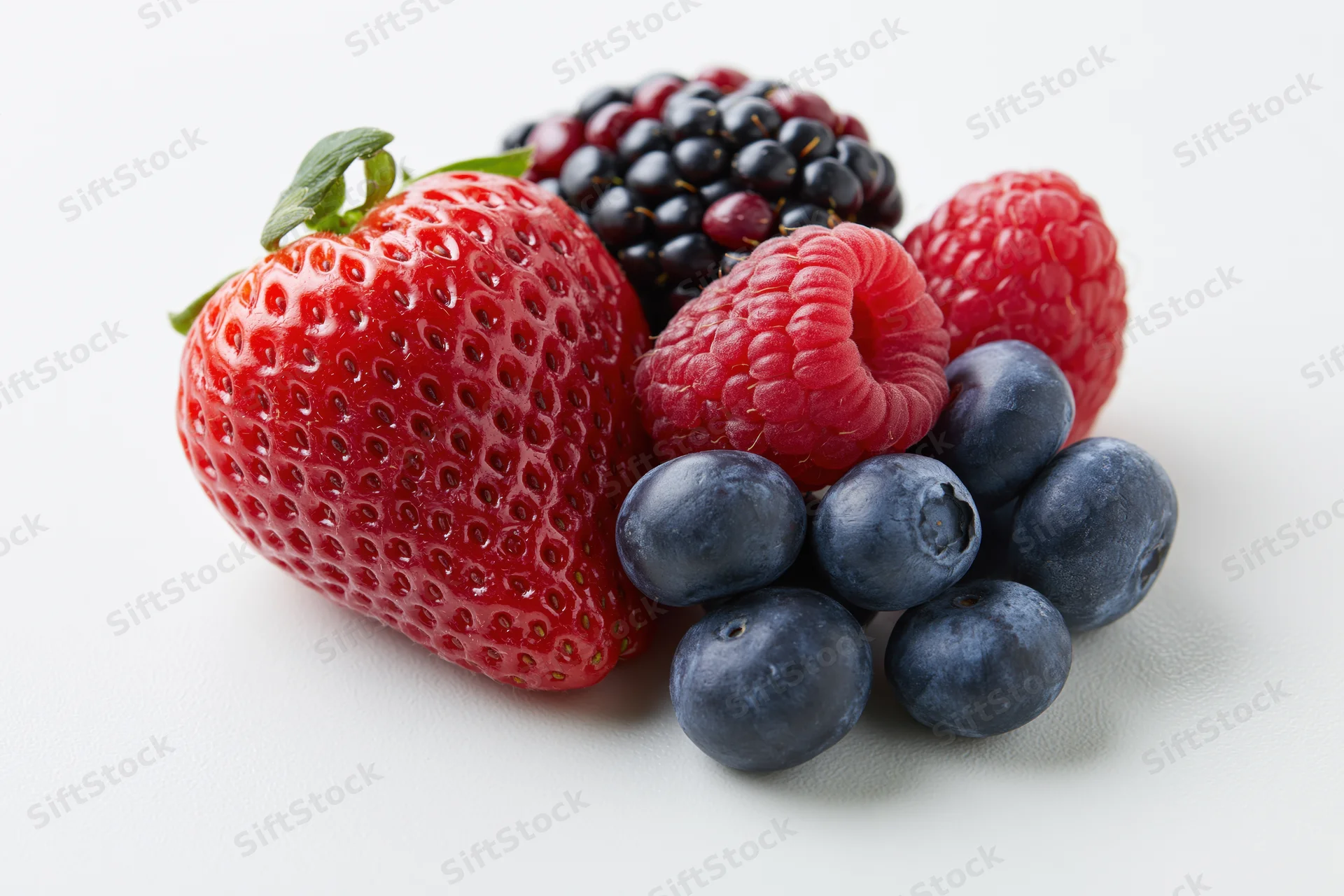 Mixed fresh berries including strawberry raspberry blueberry and blackberry arranged on white background