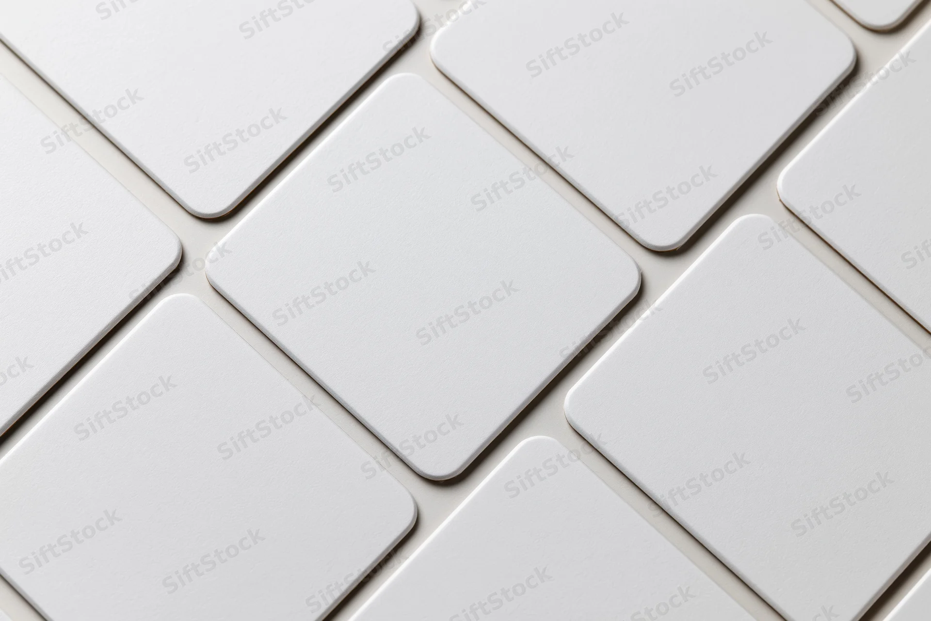 Blank white business cards with rounded corners arranged in a grid pattern on a flat surface