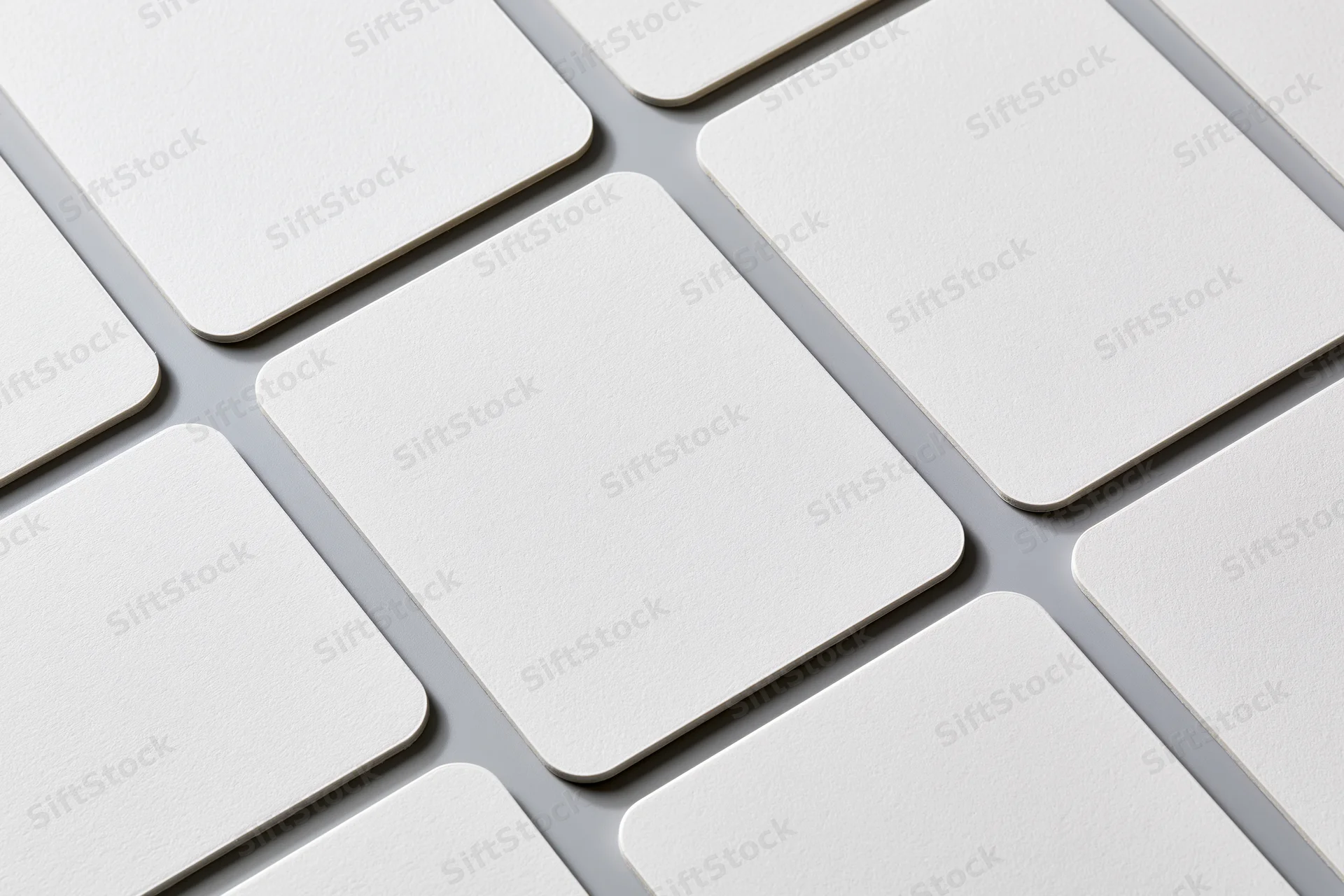 Blank white business cards with rounded corners arranged in a grid pattern on a flat surface