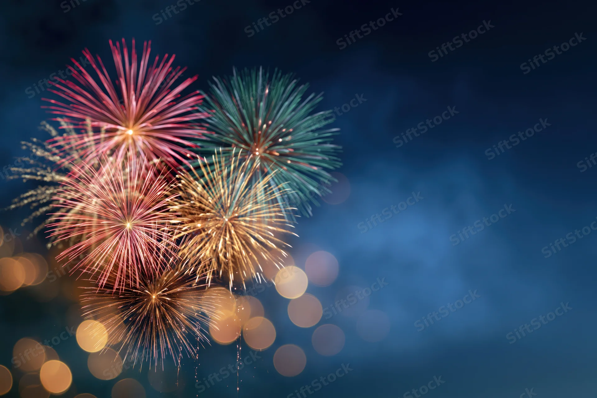 Fireworks bursting in the night sky with bokeh lights and copyspace on the right