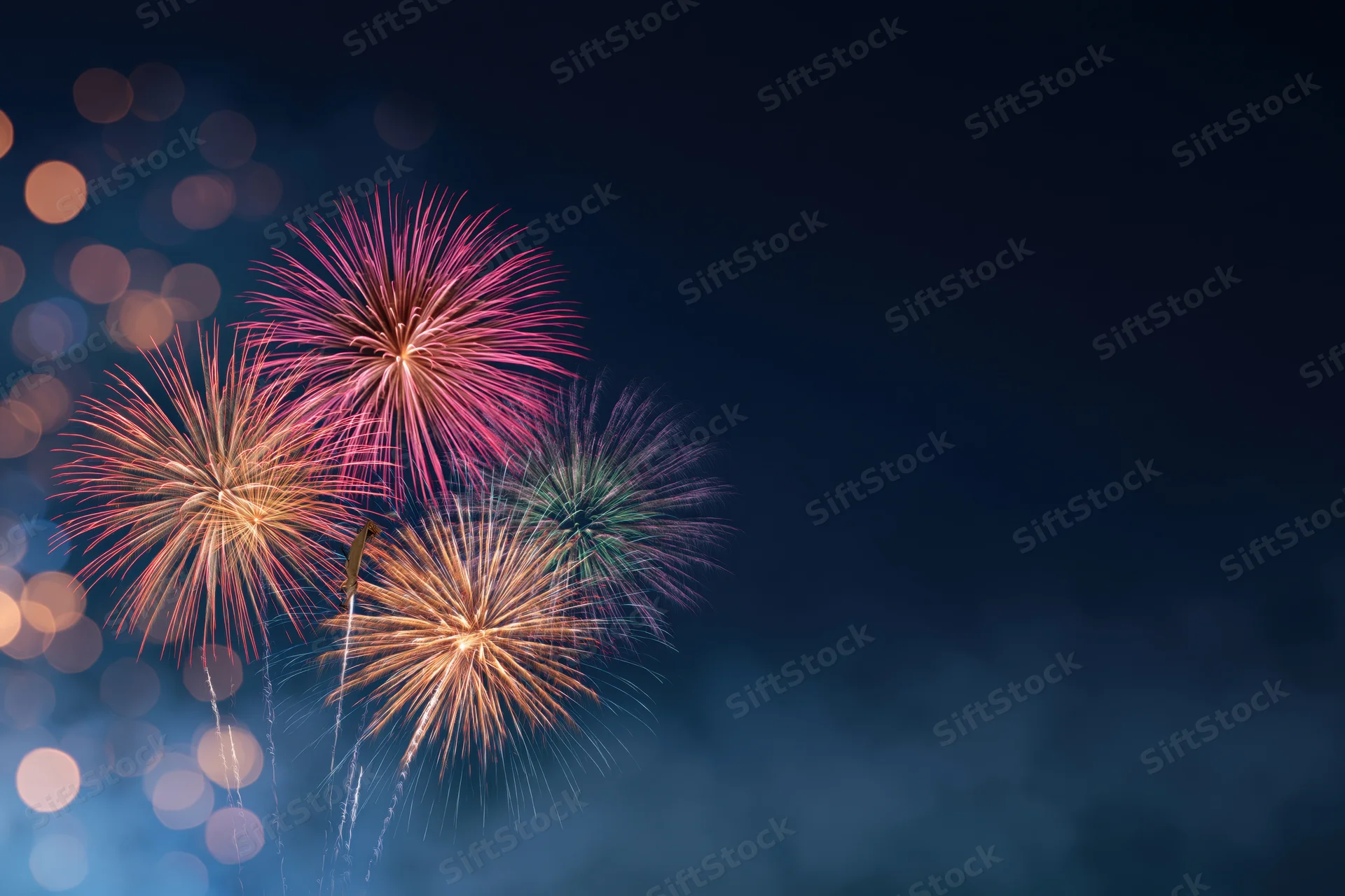 Colorful fireworks bursting in the night sky with bokeh lights and copyspace on the right