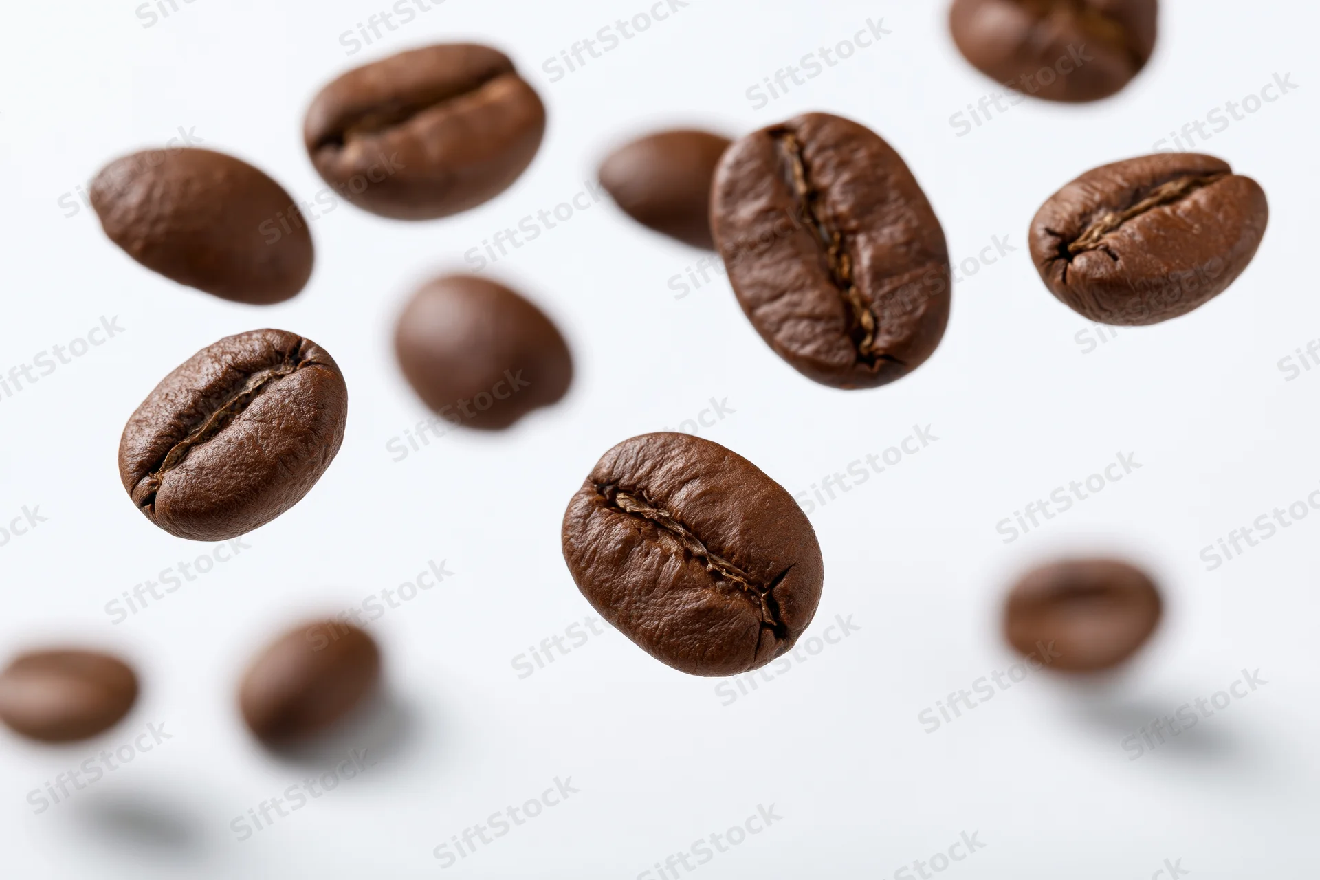 Roasted coffee beans suspended midair against a white background