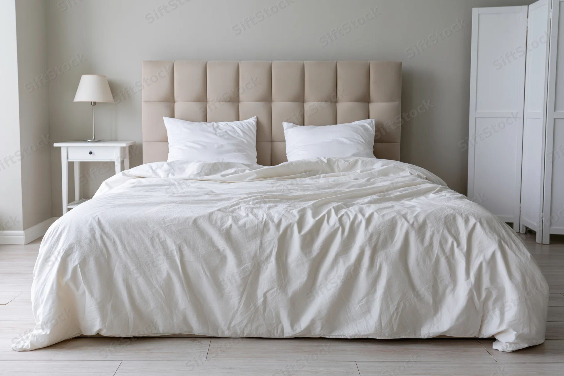 Neatly made double bed with beige tufted headboard and white bedding in a minimalist bedroom
