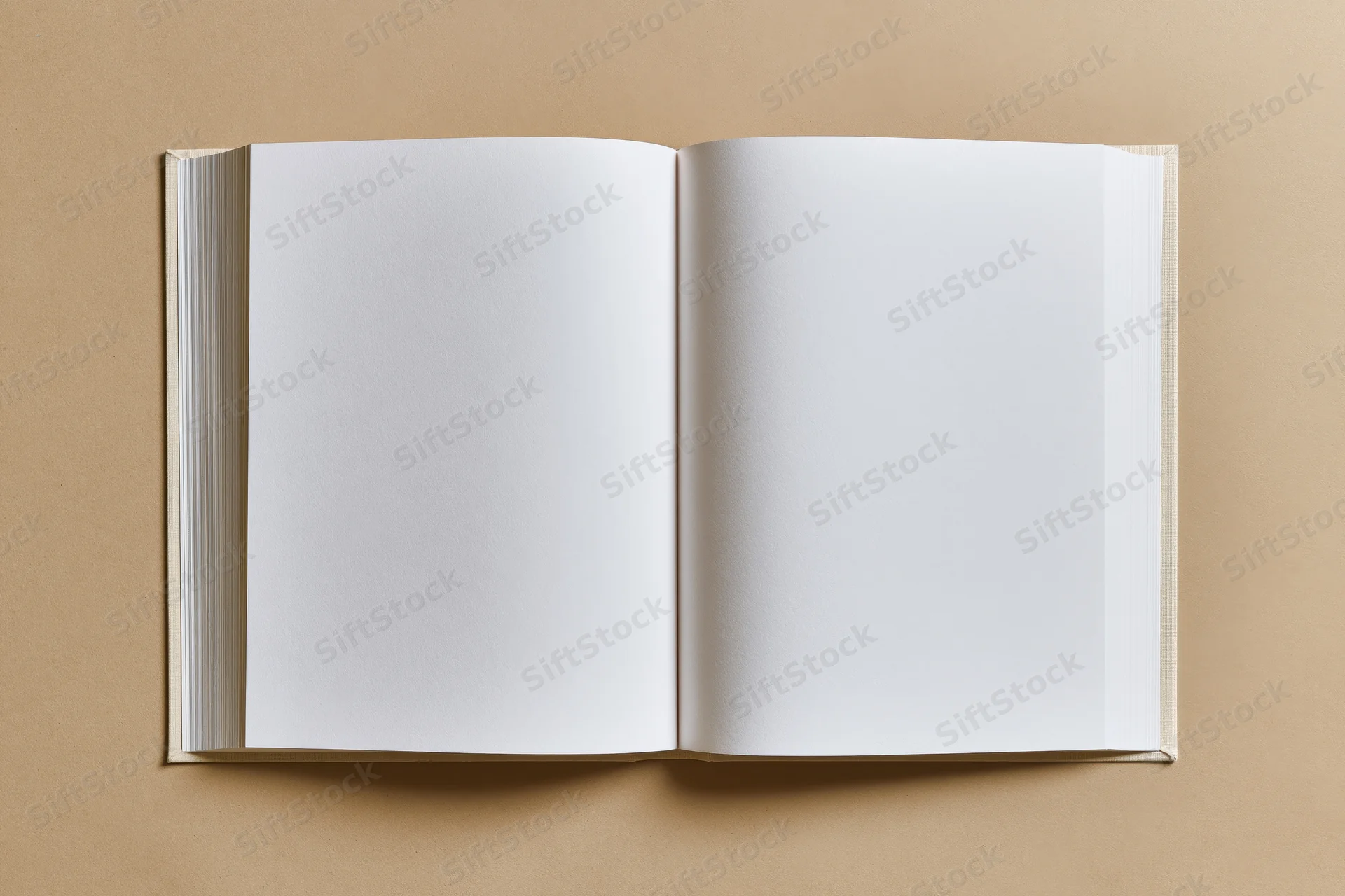 Open blank hardcover book lying flat on beige surface with empty white pages