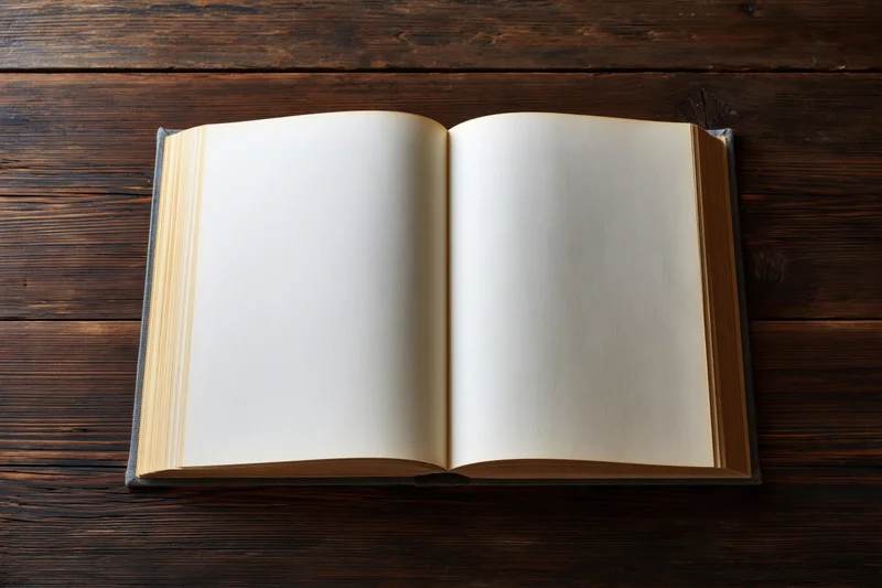Open hardcover book with blank cream pages lying flat on dark wooden table