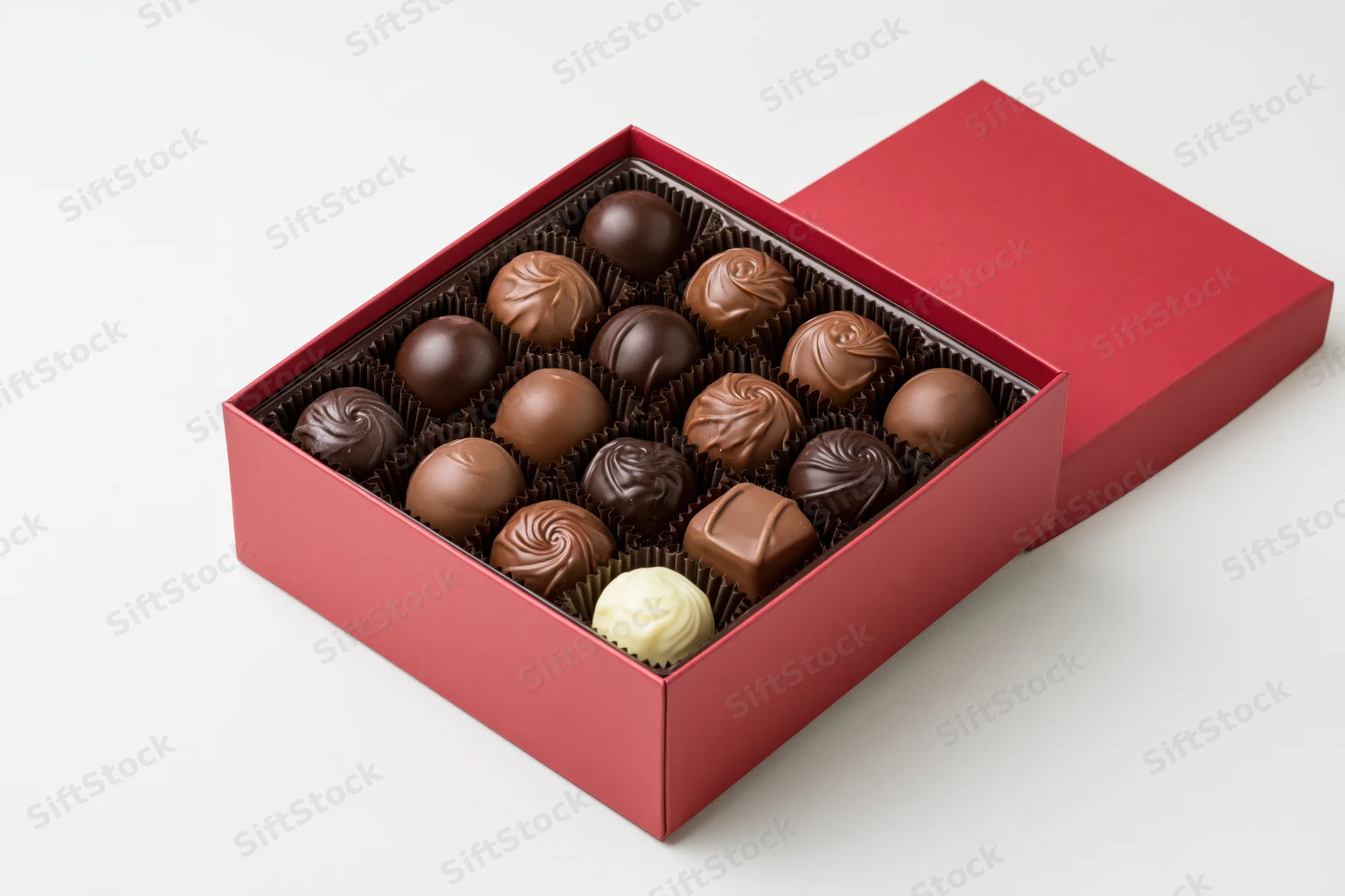 Open red gift box filled with assorted chocolates and truffles on white background