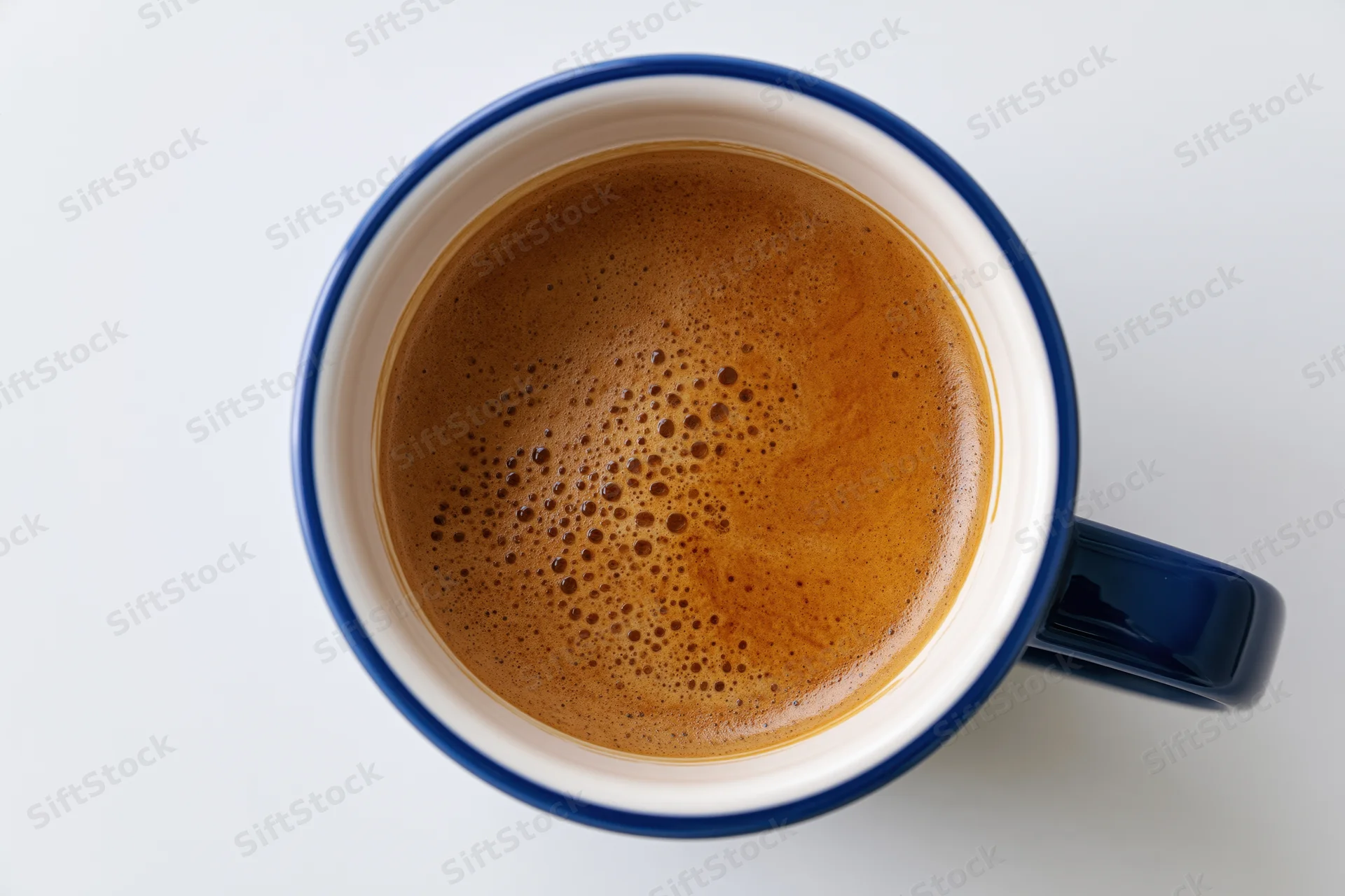 Overhead view of a blue ceramic coffee mug filled with coffee on a white surface