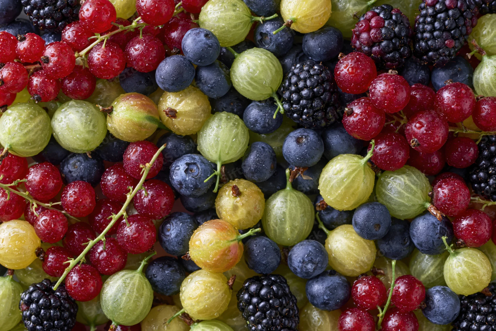 Overhead flat-lay of mixed fresh berries densely packed across the frame