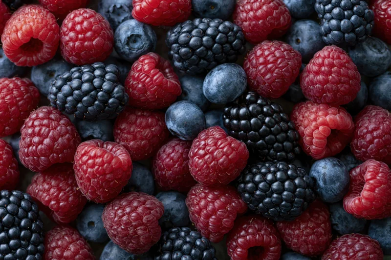 Overhead flat-lay of mixed fresh raspberries blueberries and blackberries