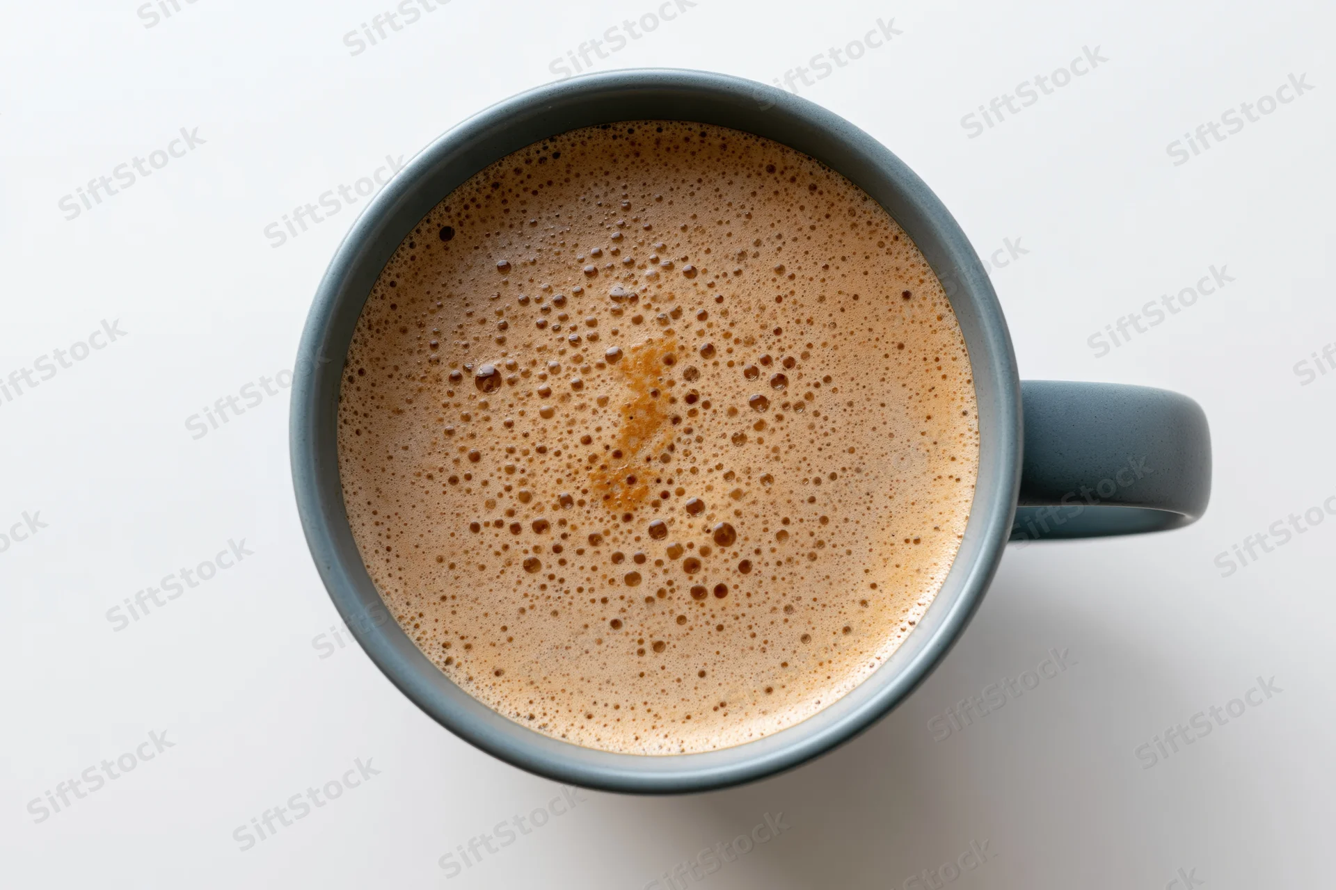 Overhead view of a grey ceramic mug filled with frothy coffee on a white surface