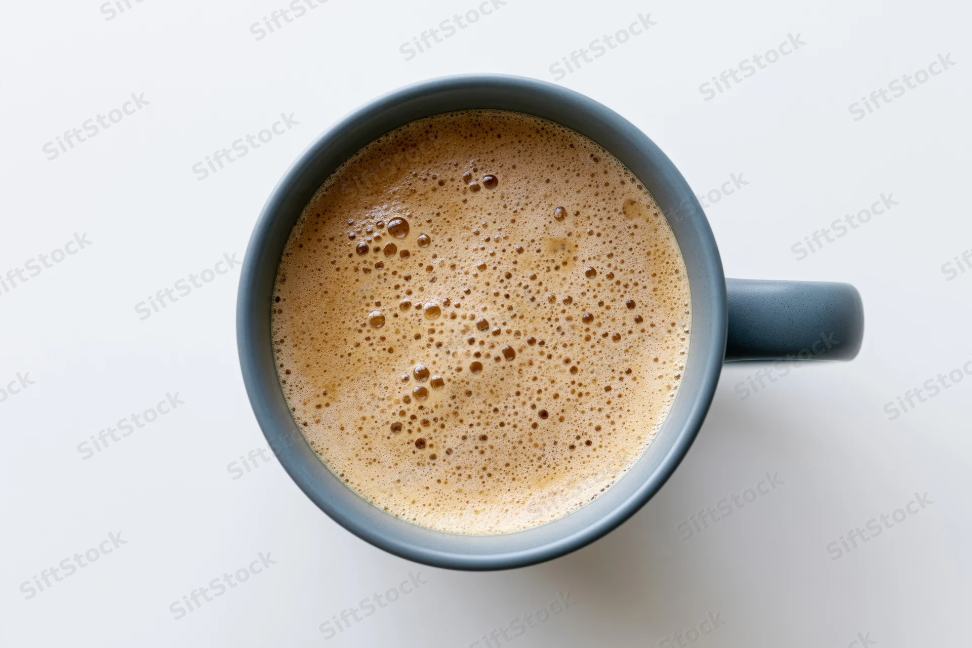 Overhead view of a grey ceramic mug filled with foamy coffee on a white surface