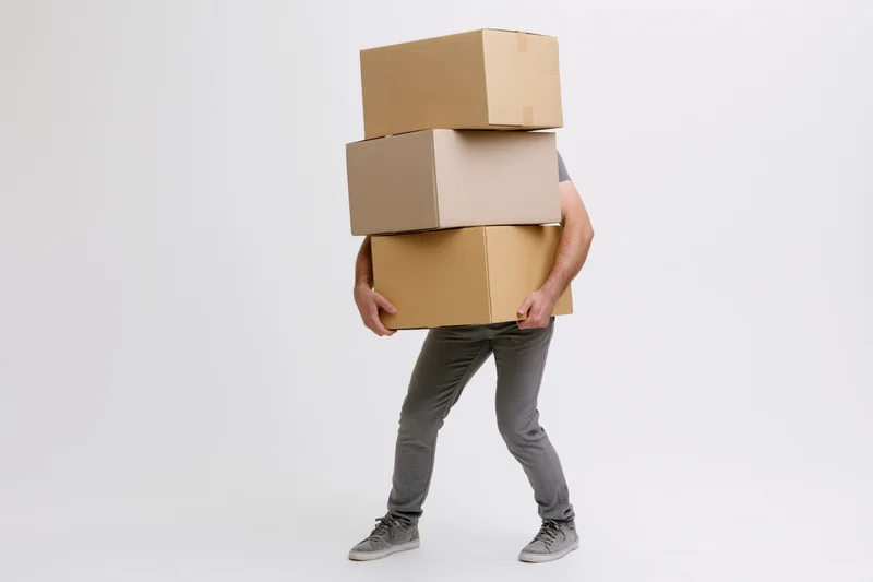 Man carrying tall stack of cardboard boxes against white background