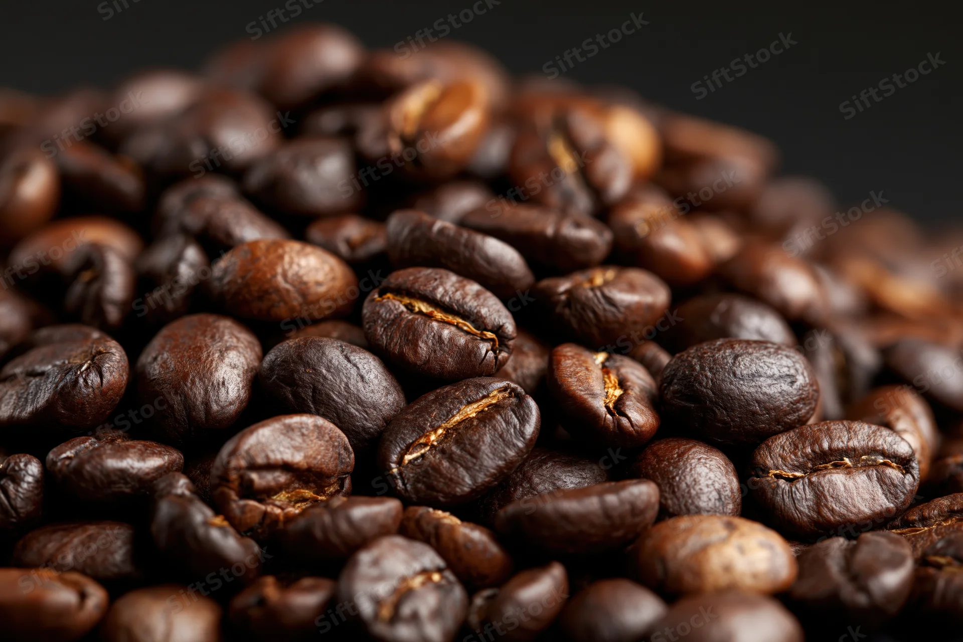 Closeup of roasted coffee beans piled together on dark background