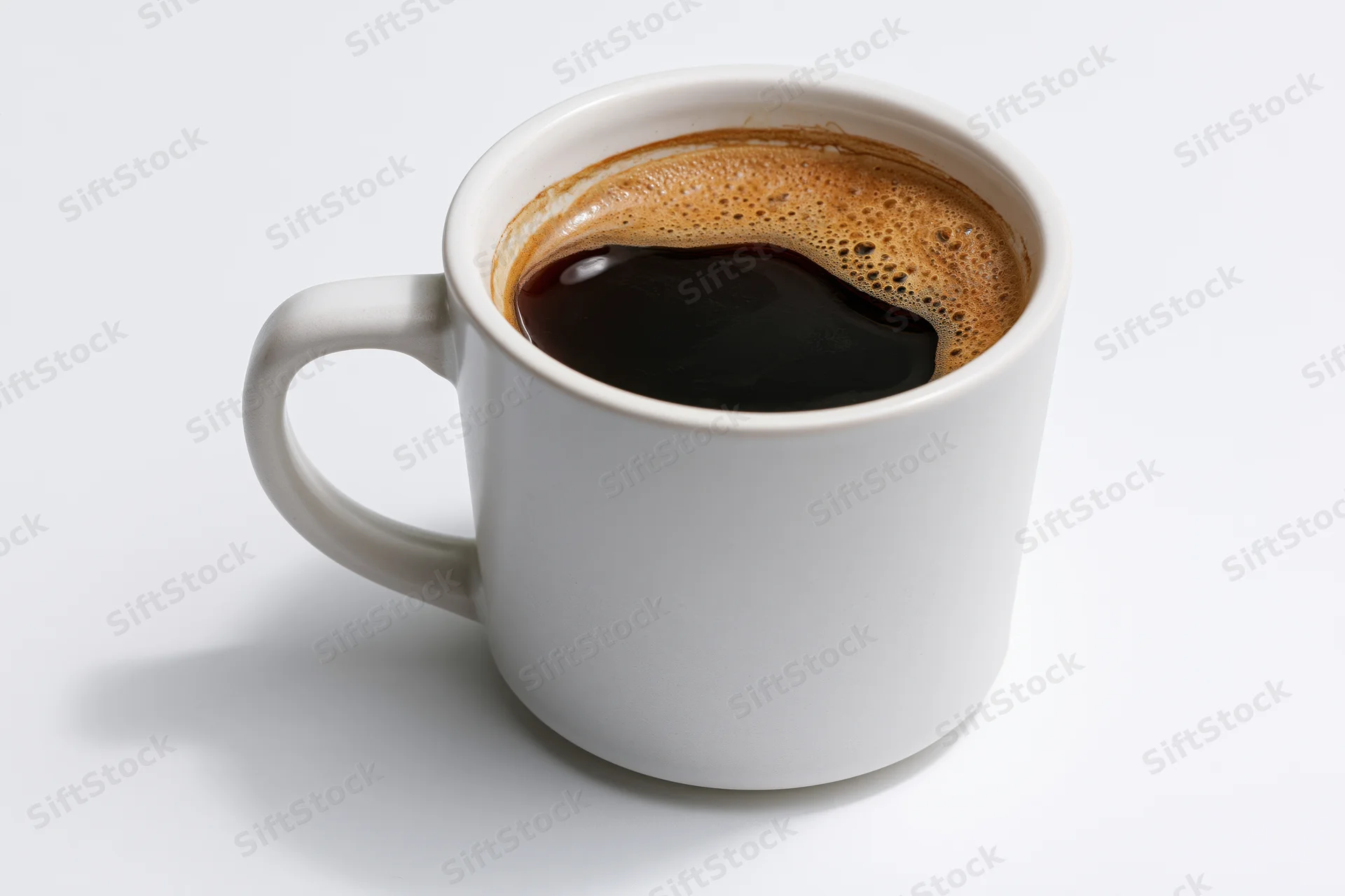 White ceramic coffee mug filled with black coffee on plain white surface