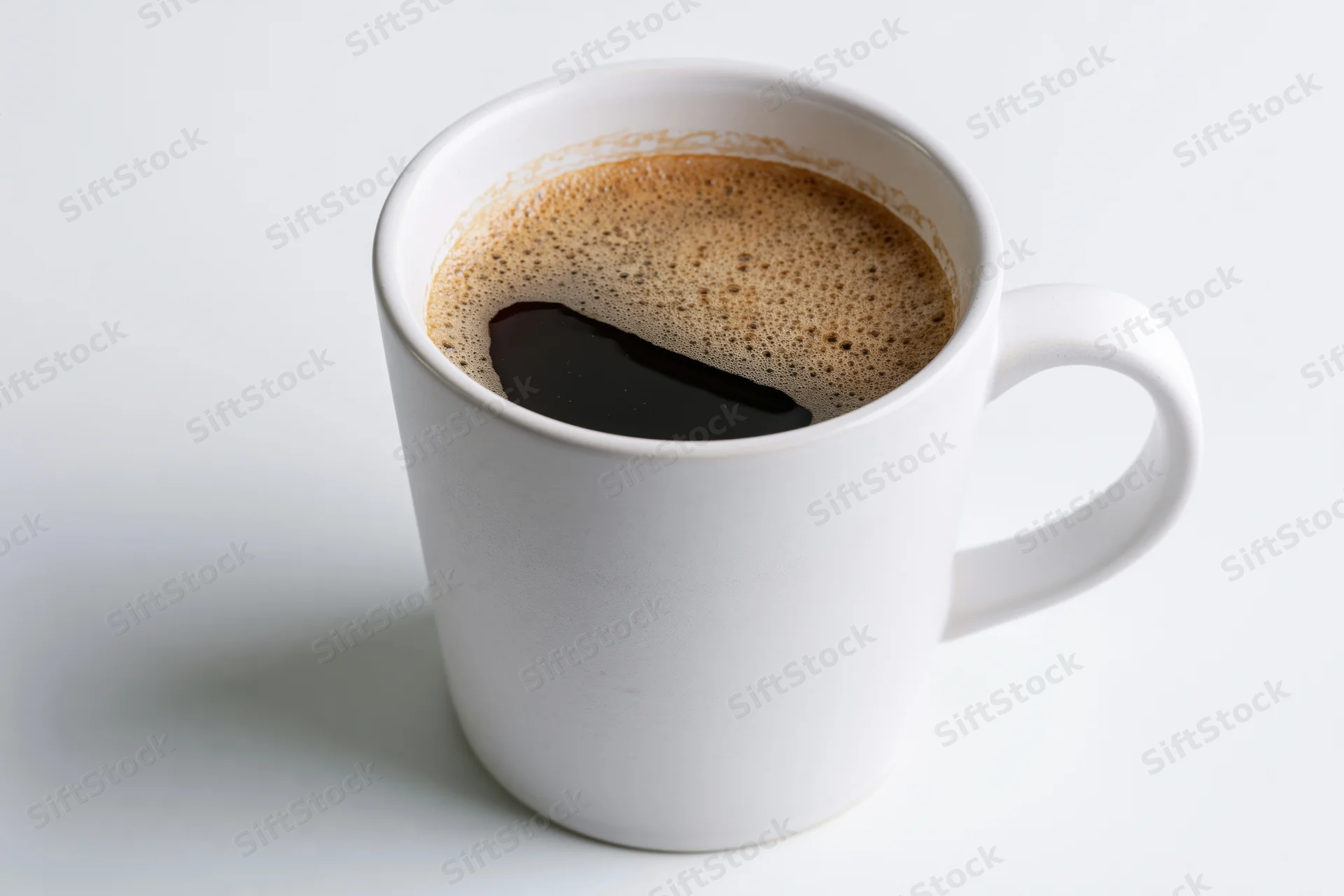 White ceramic mug filled with black coffee on plain white surface