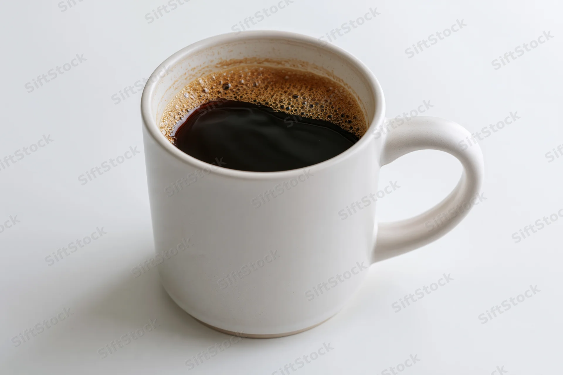 White ceramic mug filled with black coffee on a plain white surface