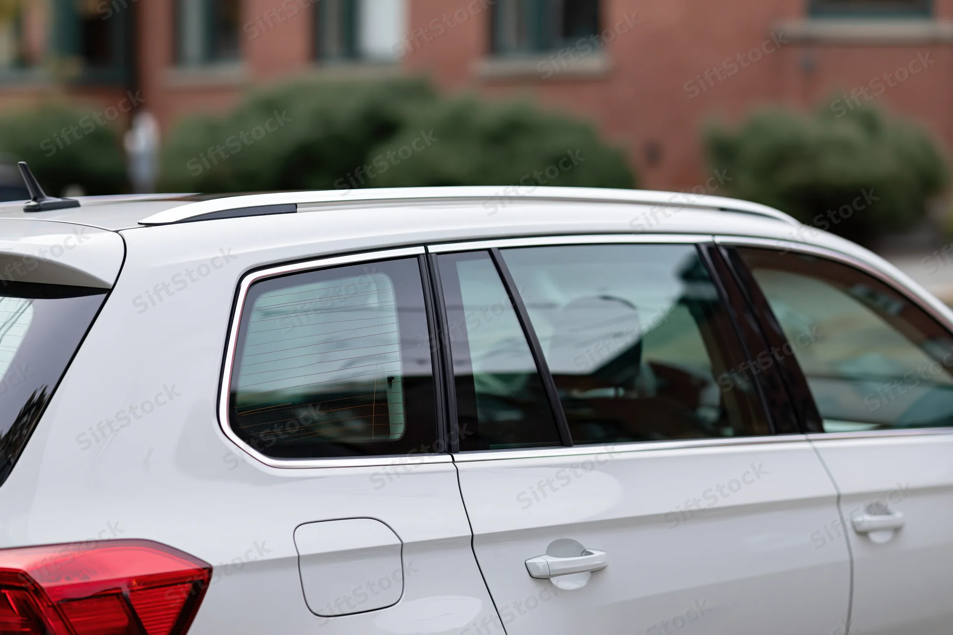 White suv parked on street shown in closeup side view with rear and windows visible