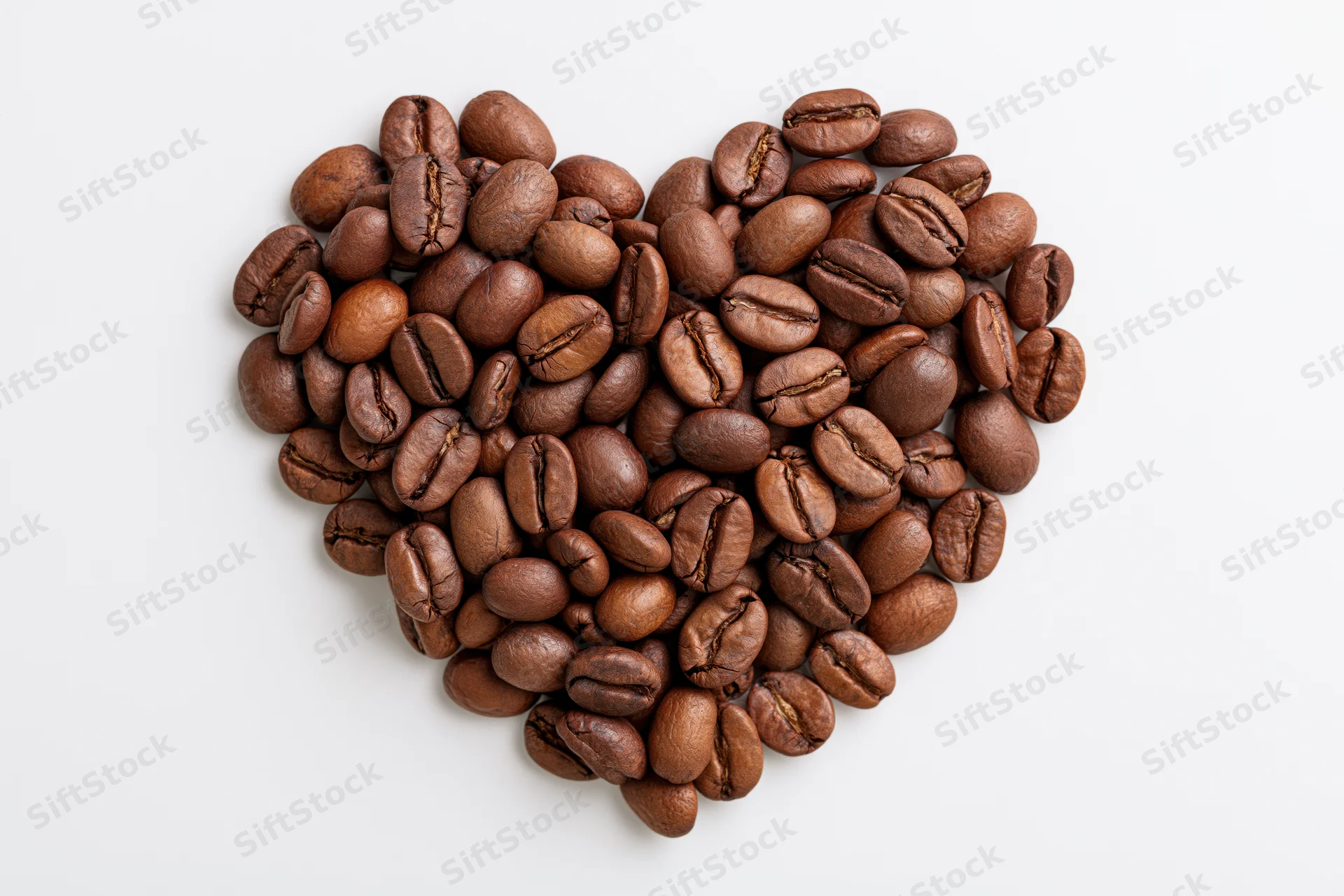 Roasted coffee beans arranged in heart shape on white background