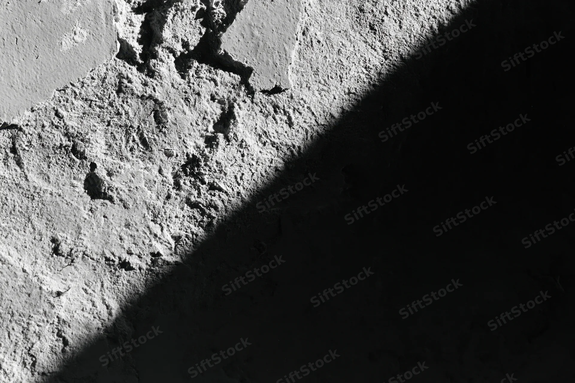Rough concrete wall with peeling texture and shadowed surface