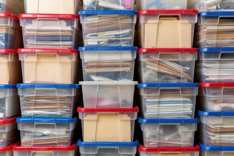 Rows of clear plastic storage bins stacked high filled with documents and files in an office setting