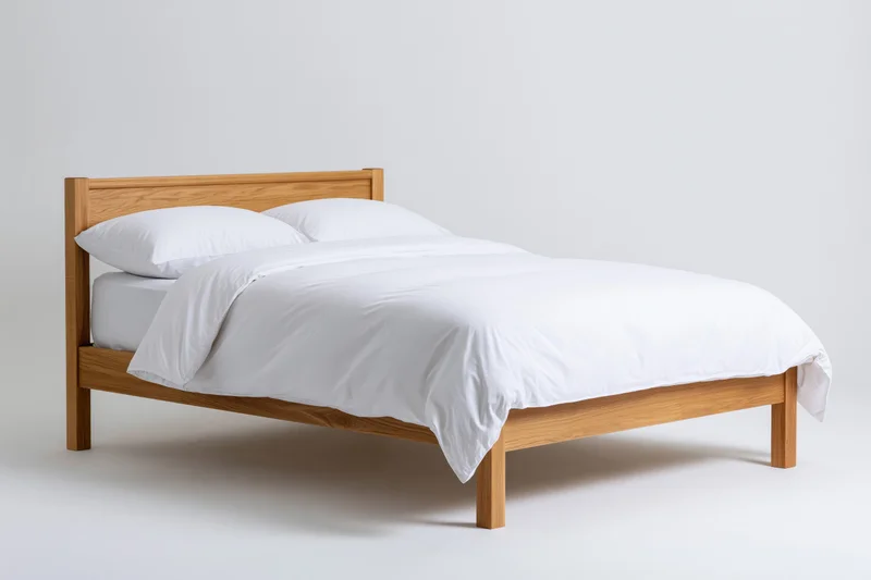 Wooden bed frame with white bedding on plain background