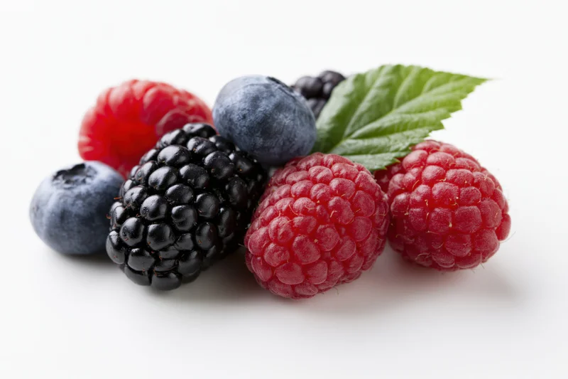 Cluster of fresh mixed berries including blackberries, raspberries and blueberries on white background