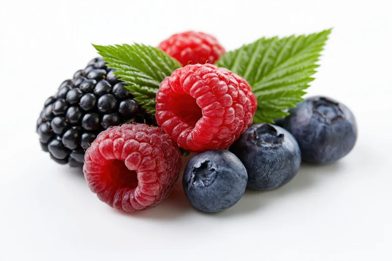 Cluster of fresh raspberries, blueberries and blackberries with green leaves on white background