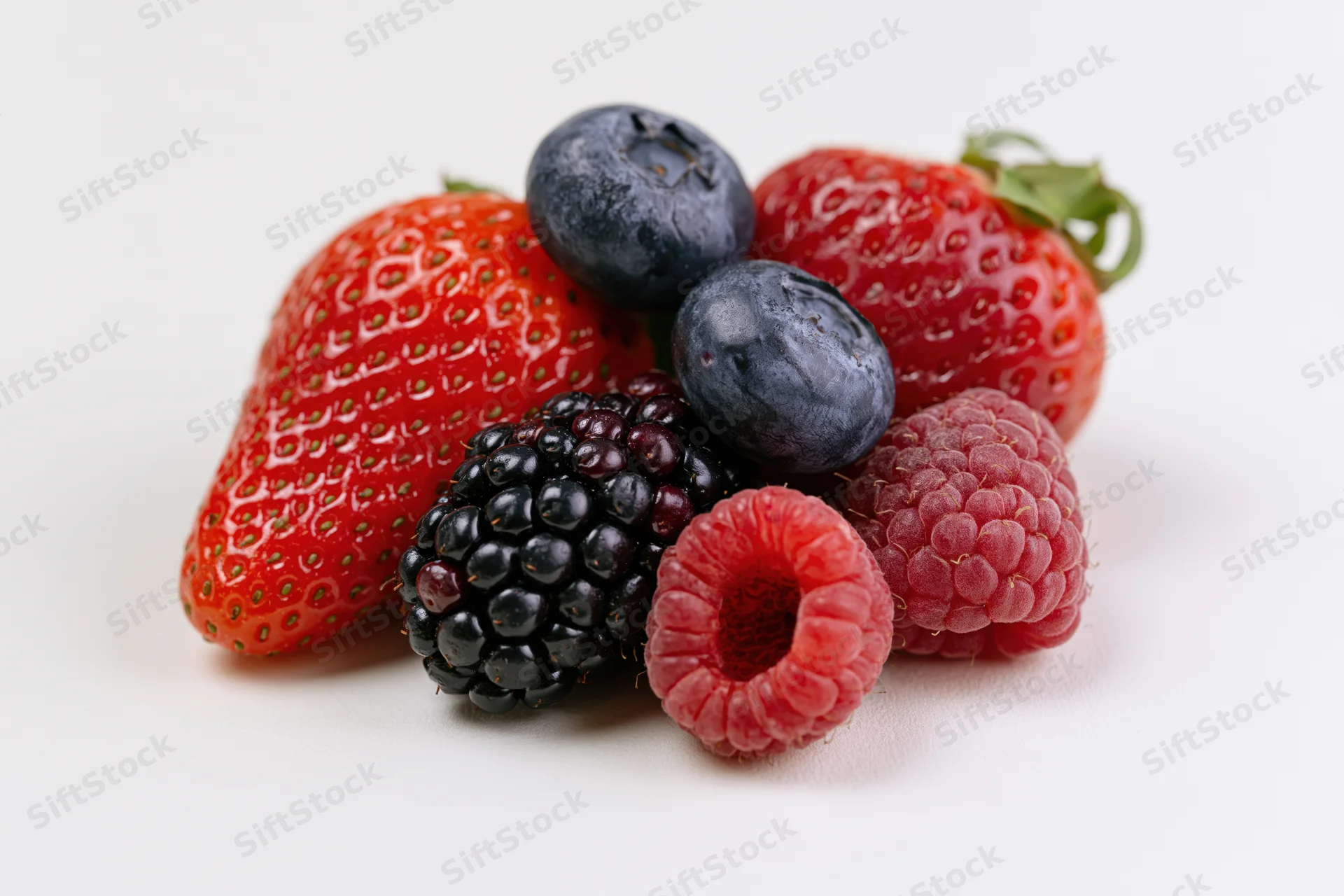 Cluster of fresh strawberries, blueberries, raspberries and blackberries on white background