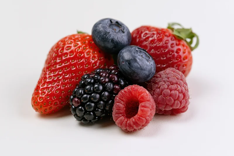 Cluster of fresh strawberries, blueberries, raspberries and blackberries on white background