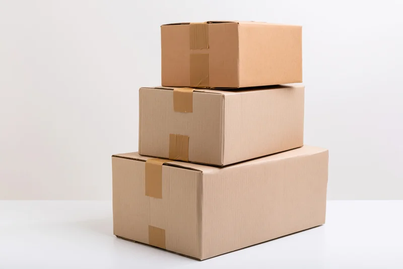Three cardboard shipping boxes stacked in a pyramid on a white surface
