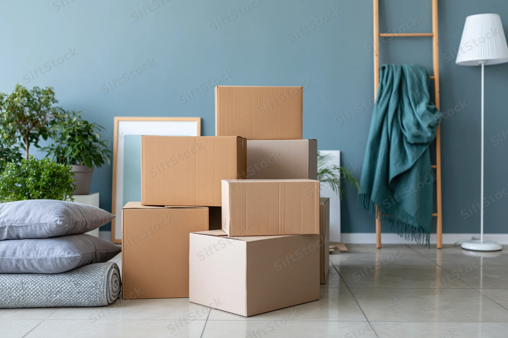 Stacked cardboard moving boxes on a light tile floor in a modern living room with plants and decor