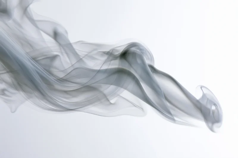Gray smoke swirling and curling against a white background