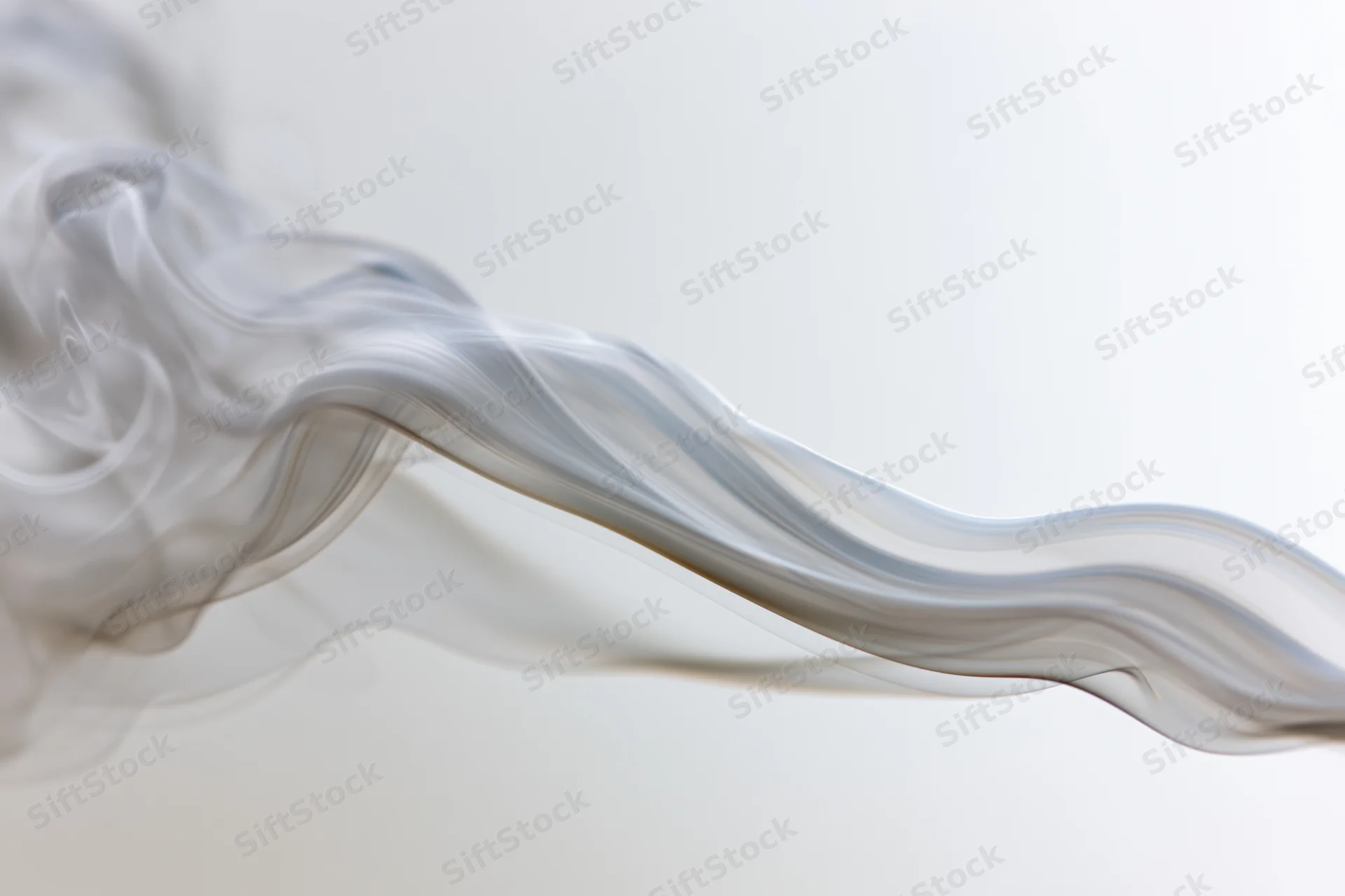 Thin wisps of grey smoke curling and drifting across a light background