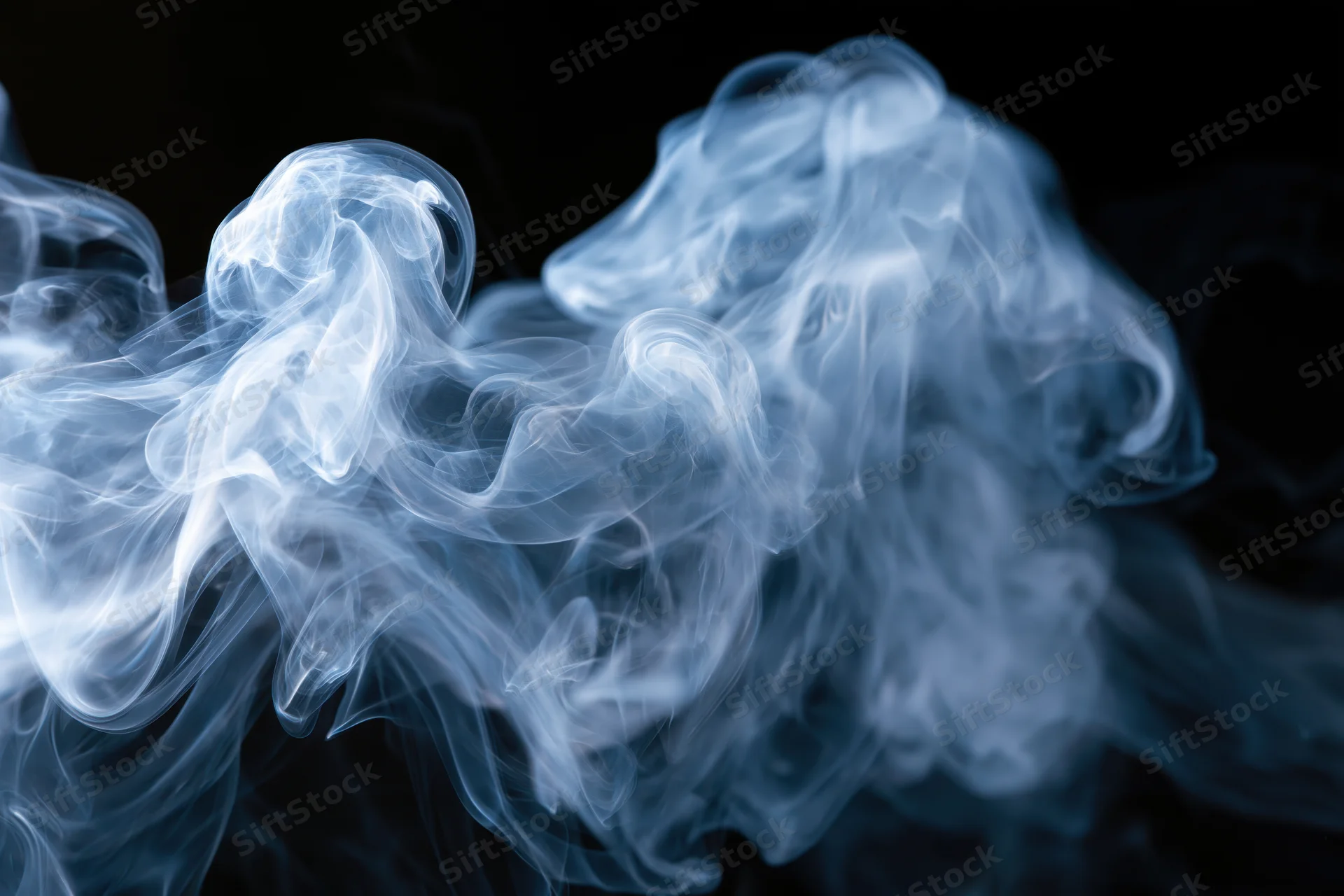Thin wisps of smoke curling and billowing in midair against a black background
