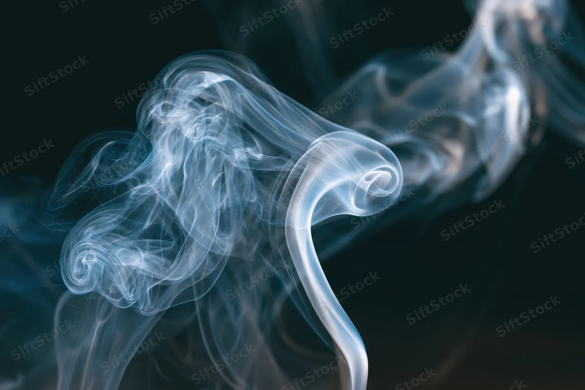Thin wisps of smoke curling and billowing in midair against a dark background