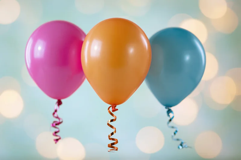 Three colorful latex balloons floating against a soft bokeh background