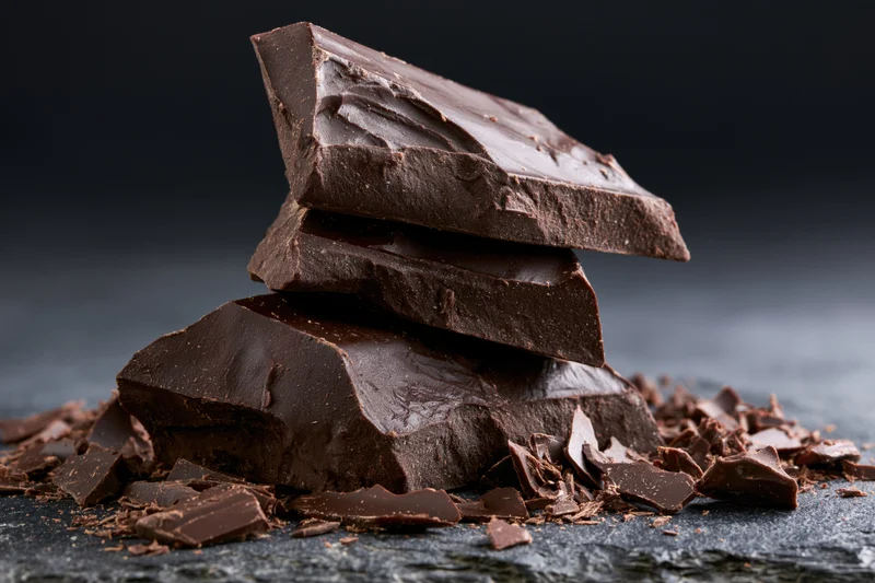 Broken dark chocolate chunks stacked unevenly on a slate surface