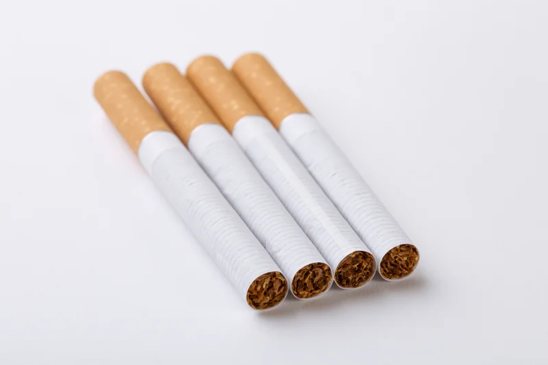 Four unlit cigarettes arranged in parallel on a white surface
