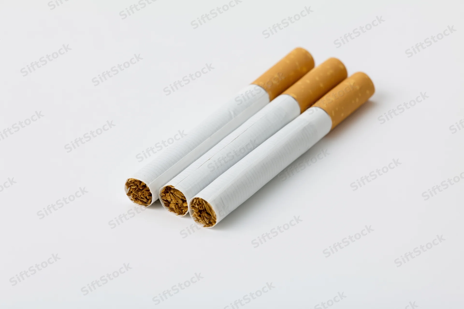 Three unlit cigarettes arranged in parallel on a white surface