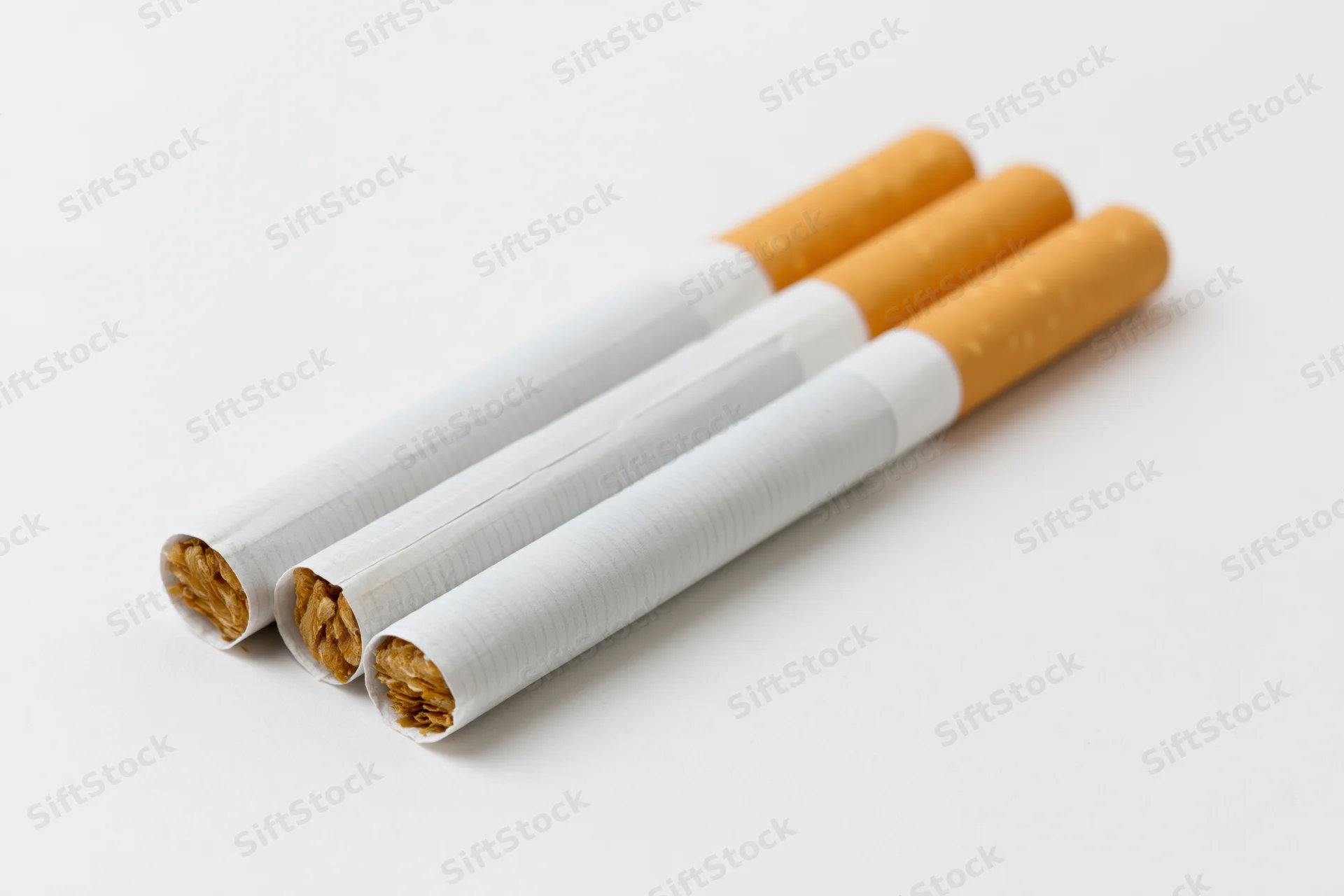 Three unlit cigarettes arranged in parallel on a white surface