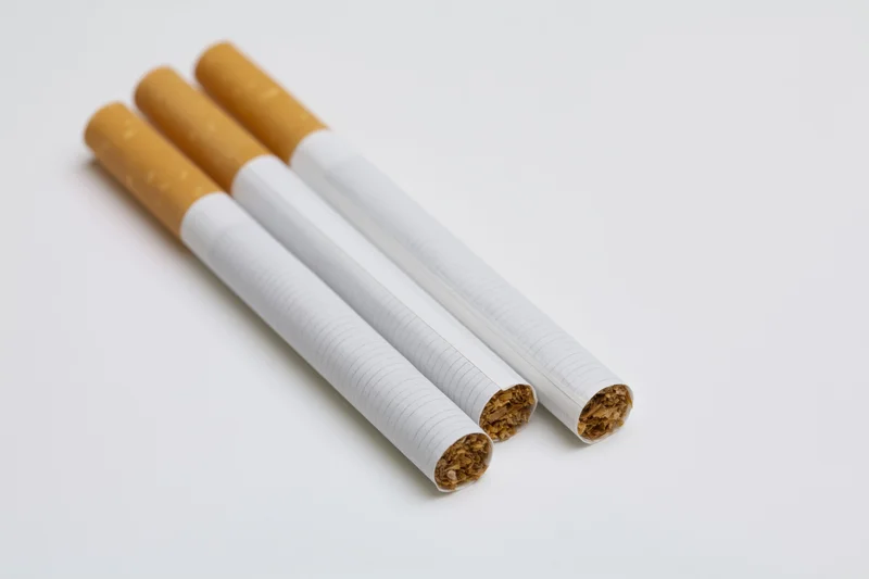 Three unlit cigarettes arranged in parallel on a white surface